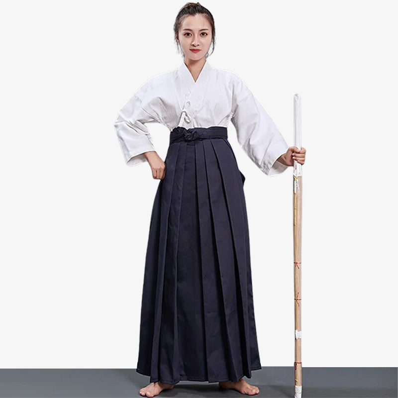 Hakama femme porté par une pratiquante d'arts martiaux japonais avec un keikogi blanc et un shinai en bois