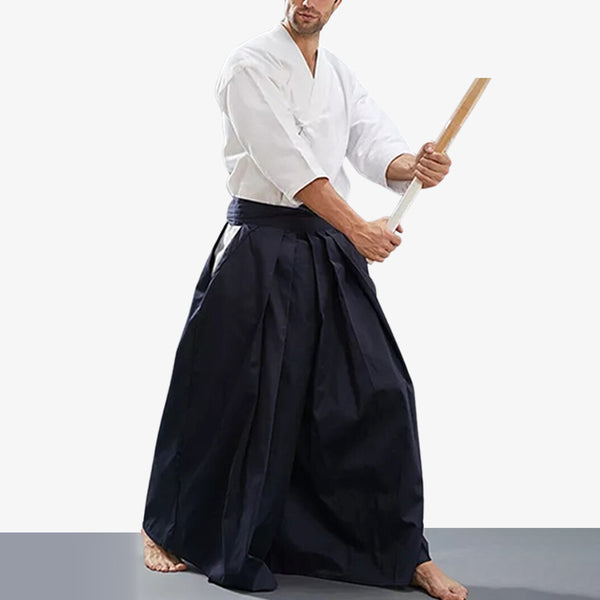 Un pratiquant d'art martial japonais est habillé avec un hakama kendo de couleur bleu. Son équipement se compose d'un vetement keikogi blanc et d'un katana en bois shinai