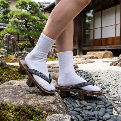 Geta japonaises portées avec des chaussettes tabi blanches dans un jardin japonais