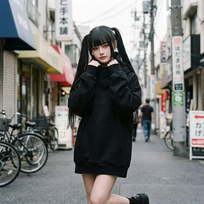 Hoodie noir oversize porté par une femme à Harajuku, le col cheminée enroulé autour du cou