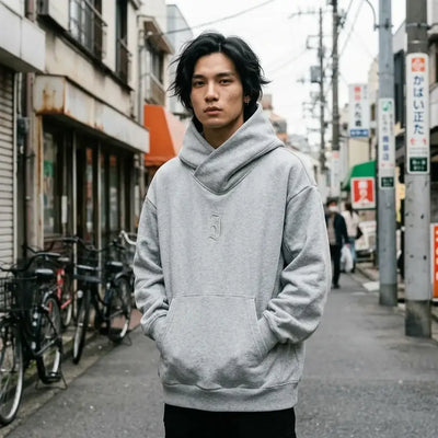 Sweat à capuche gris Harajuku avec un col cheminée croisé, porté oversize avec les mains dans la poche kangourou, à Harajuku.