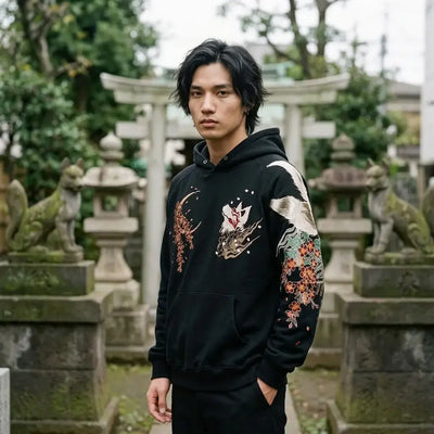 Le sweat renard japonais porté près d'un petit sanctuaire Inari à Tokyo, avec des statues de renard en pierre à côté de lui.