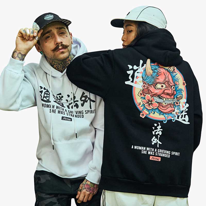 Un homme et une femme portent un hoodie Oni japonais avec un motif de démon et des kanji imprimés