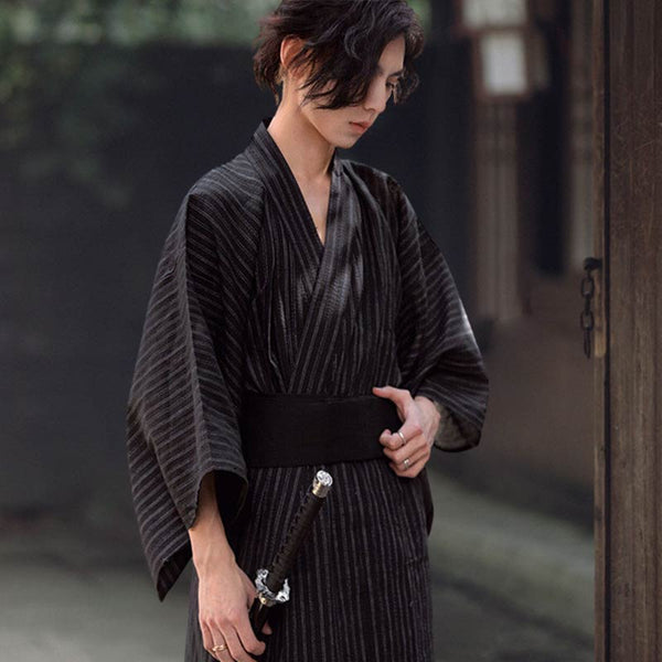 Enfilez un kimono homme japonais pour un style traditionnel samouraï. L'homme tient dans sa main un ceinture obi noir et un katana