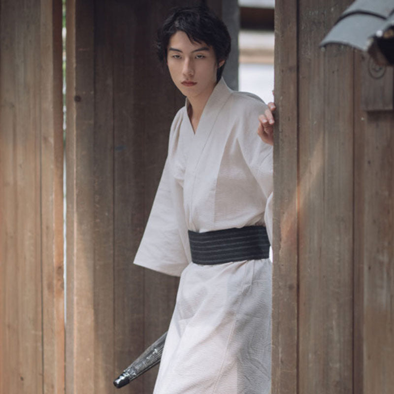 Un homme est habillé avec un kimono Japon blanc. Le kimono yukata est fermé avec une ceinture Obi