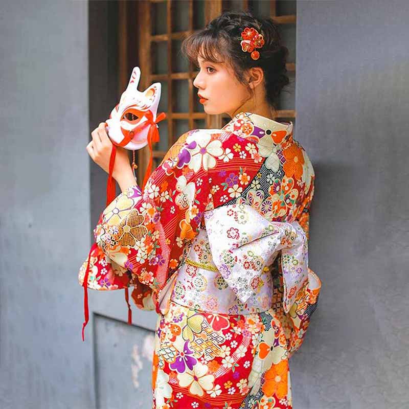Kimono japonais femme rouge aux imprimés de fleurs de sakura, porté avec un masque kitsune renard
