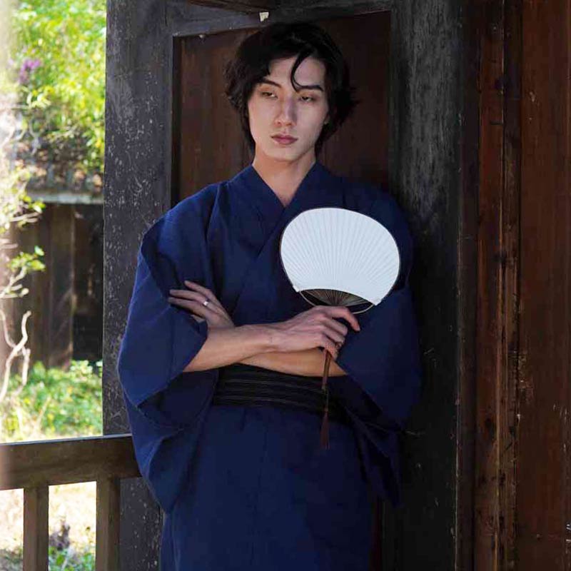 Un homme porte un kimono japonais traditionnel de samourai avec un eventail sensu. C'est un eventail japonais de couleur blanche