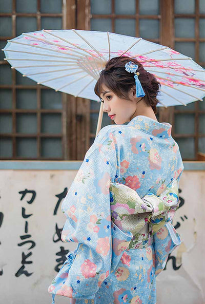 Robe kimono ornée de motifs floraux japonais, une femme se tient gracieusement, tenant un wagasa traditionnel