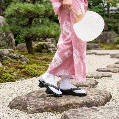 Sandales geta en bois portées avec un kimono rose dans un jardin japonais