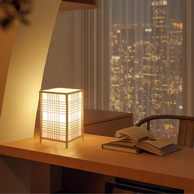 Lampe de bureau japonaise posée sur un bureau avec des livres et une vue sur la ville