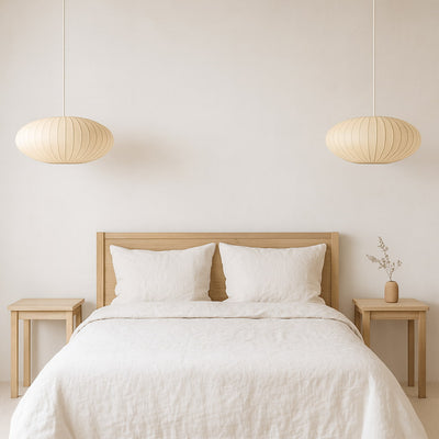 Chambre avec tête de lit en bois, linge de lit blanc et suspensions en papier japonais
