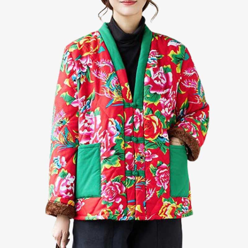 Une femme est habillée avec un manteau style japonais. La veste japonaise s'enfile par dessus un kimono femme.  Le hanten femme est imprimé avec des dessins floraux. la veste matelassée est de couleur rouge, les poches et le col du tissu brodé sont verts