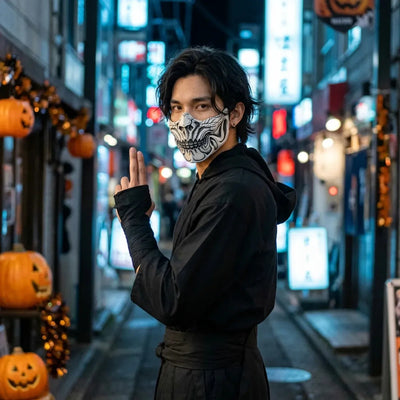Masque crâne d'Halloween porté avec une tenue ninja noire, regard par-dessus l'épaule dans une rue de Tokyo déserte.