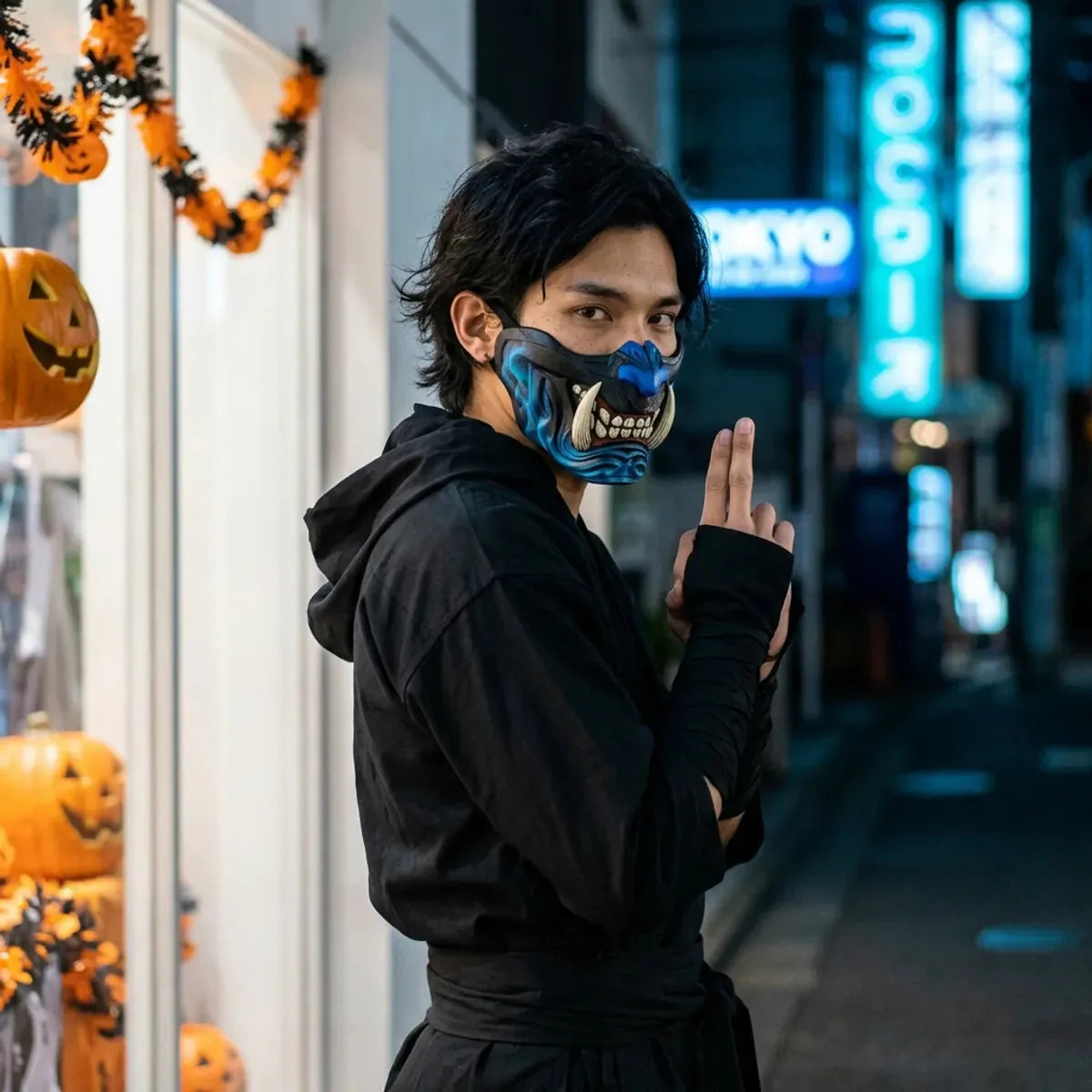 Masque demon halloween porte avec une tenue de ninja noire, regard par-dessus l epaule dans une rue vide de tokyo