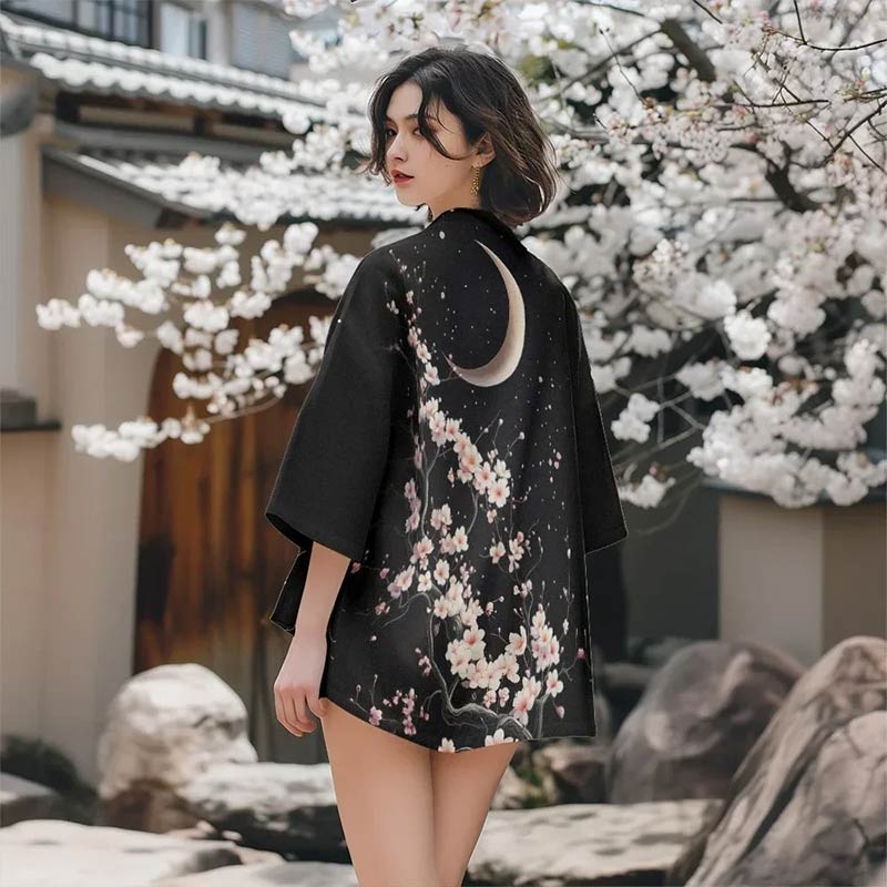 Une femme porte un kimono à motif Sakura mettant en valeur des motifs raffinés de fleurs de cerisier et le symbole de la lune, très prisés dans le textile traditionnel japonais