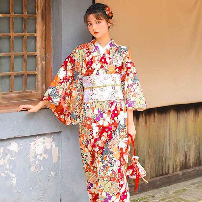 Femme portant un kimono japonais rouge à motifs de sakura, ceinturé d'un large obi japonais