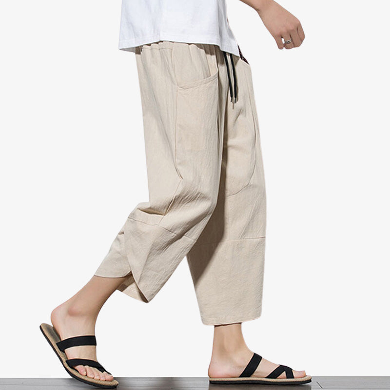 Un homme marche avec un pantacourt japonais beige et des sandales en bois