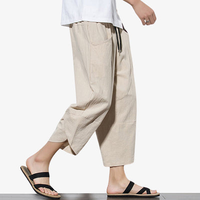 Un homme marche avec un pantacourt japonais beige et des sandales en bois
