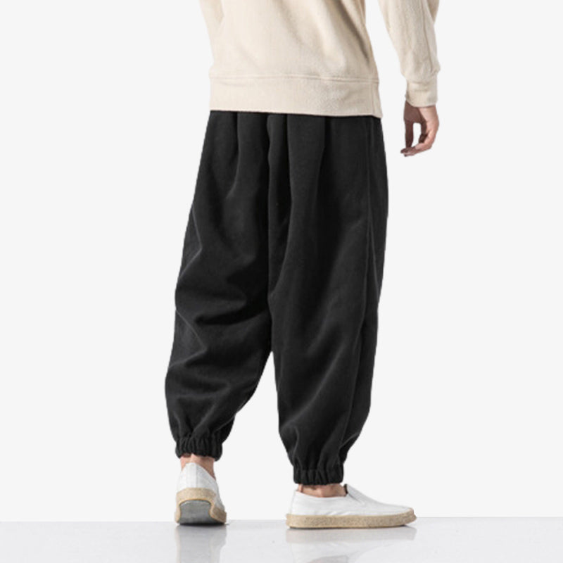 un homme est vêtu d'un pantalon japonais cargo noir de couleur uni et au style minimaliste