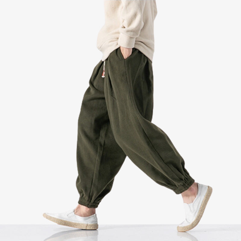 Pour un style streetwear japonais ou traditionnel, un homme marche avec un pantalon japonais homme souple de couleur marron
