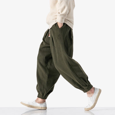 Pour un style streetwear japonais ou traditionnel, un homme marche avec un pantalon japonais homme souple de couleur marron