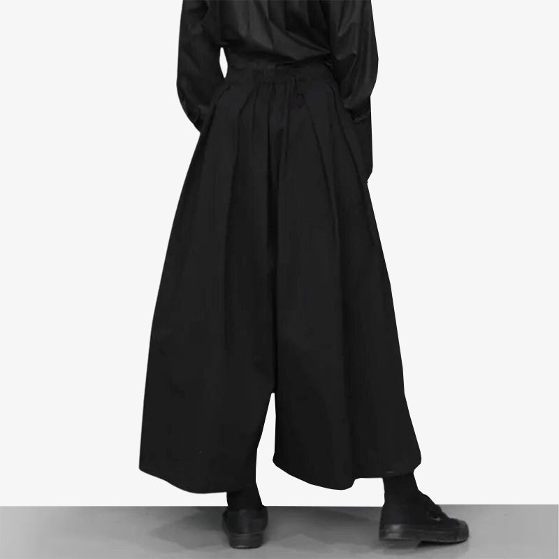 Ce pantalon jupe japonais femme fashion est de couleur noir. La femme est habillée avec des chaussures noir pour un style japonais Techwear et urbain
