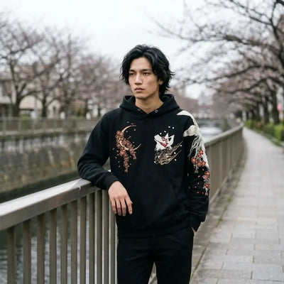 Le pull kitsune brodé porté au bord de la rivière Meguro à Tokyo, sous un ciel gris.
