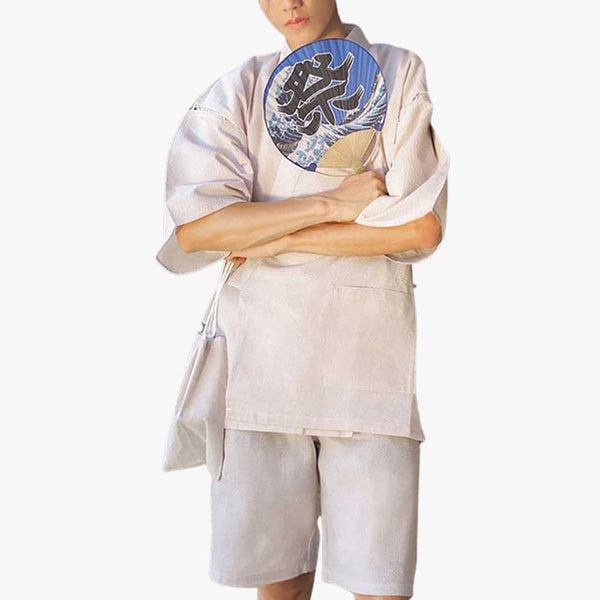 Ce pyjama japon homme est de couleur blanche. C'est un ensemble kimono avec un short et un haut de vêtement japonais traditionnel. L'homme porte aussi dans la main un éventail Uchiwa