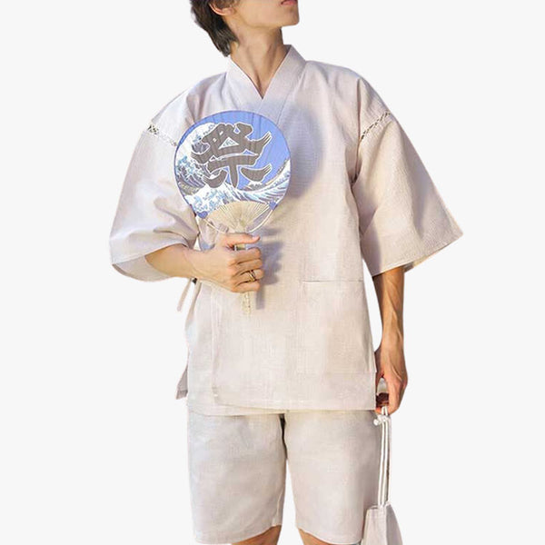 Ce pyjama japonais homme est un jinbei. C'est un kimono d'été. L'homme tient dans la main un éventail Uchiwa
