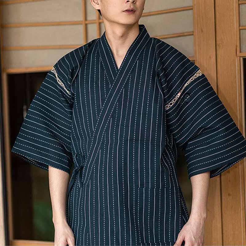 Un homme est habillé avec un pyjama kimono japonais. Ce vêtement traditionnel est un Jinbei pour homme avec un motif de rayures