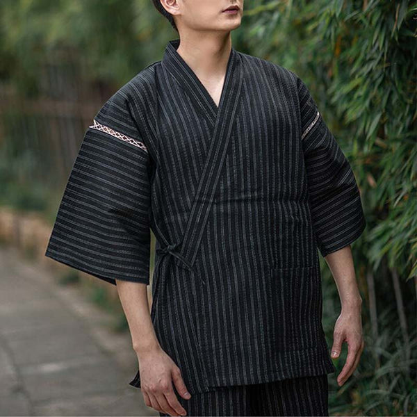 Un homme est habillé avec un pyjama style japonais. Cet habit japonais traditionnel est un Jinbei. C'est un short court et un haut de kimono