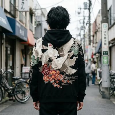 Le dos du sweat renard kitsune : un grand renard blanc à neuf queues au-dessus de pivoines rouges et de fleurs orange.