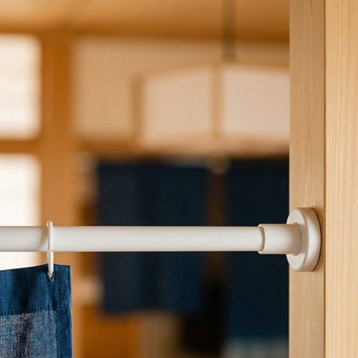 Tringle à tension soutenant un rideau noren indigo dans une embrasure en bois