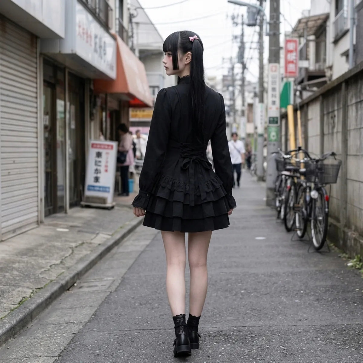 Vue arrière de la mini robe noire, avec le laçage en ruban à la taille et les deux volants de la jupe.