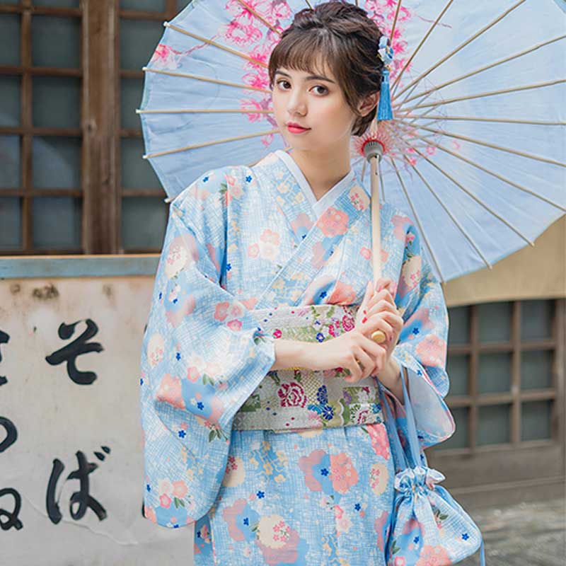 Robe kimono traditionnelle imprimée de motifs floraux japonais, la femme tient élégamment un wagasa, révélant des motifs délicats
