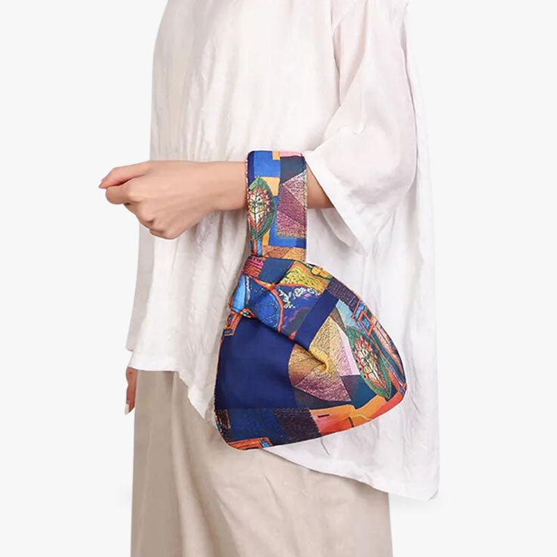 Une femme porte au bras un sac a noeud. C'est un sac japonais traditionnel de couleur bleu et en coton