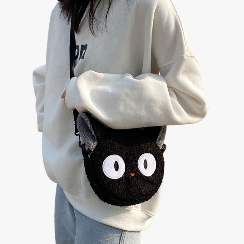 Une femme porte sur l'épaule un sac kawaii chat de couleur noir. Le sac japonais en bandoulière a une matière douce
