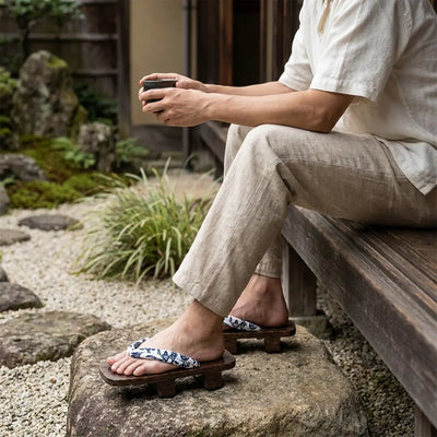Sandales geta portées avec des chaussettes tabi blanches, homme assis dans un jardin japonais