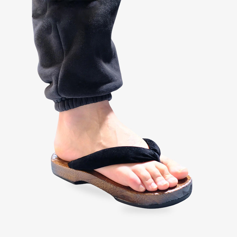 Sandales zori japonaises simples et élégantes, portées au pied droit, en bois avec lanière en soie noire