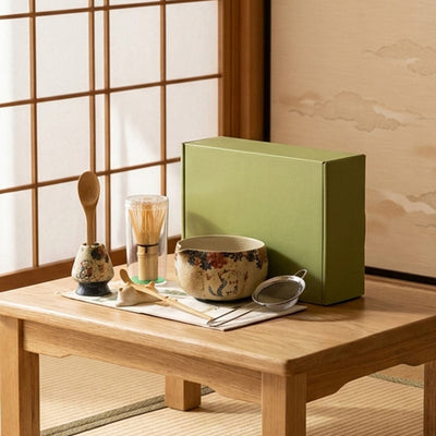 Coffret vert et accessoires du set matcha posés sur une table en bois dans une pièce japonaise
