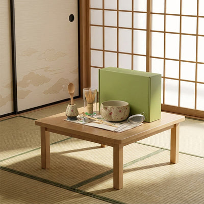 Table en bois avec set à matcha cérémoniel et coffret vert dans une pièce japonaise traditionnelle