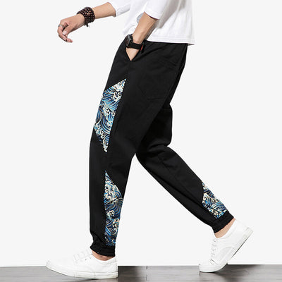 un homme marche avec un pantalon slim japonais de couleur noir. Des motifs de vagues japonaises sont imprimés sur le tissu en coton noir