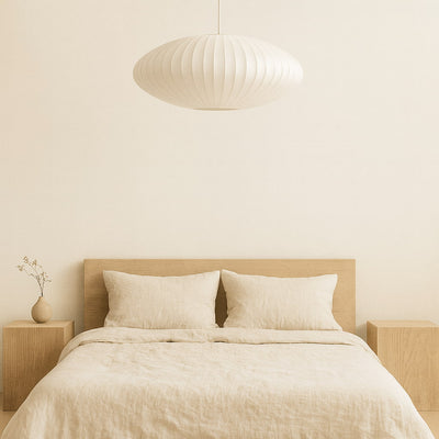 Chambre beige avec un lit, des tables de chevet et une suspension japonaise suspendue