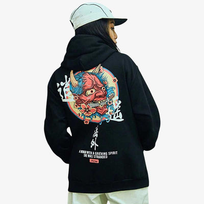 Une femme porte un hoodie Oni noir en coton avec un motif de démon japonais rouge