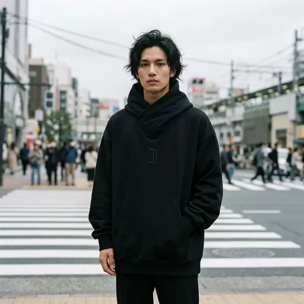 Sweat noir oversize à col croisé porté à un passage piéton à Tokyo par temps gris