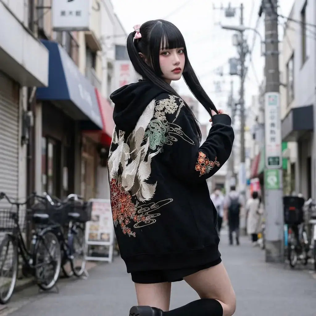 Sweat kitsune porté oversize par une femme à Tokyo, qui regarde par-dessus son épaule le renard blanc dans le dos.