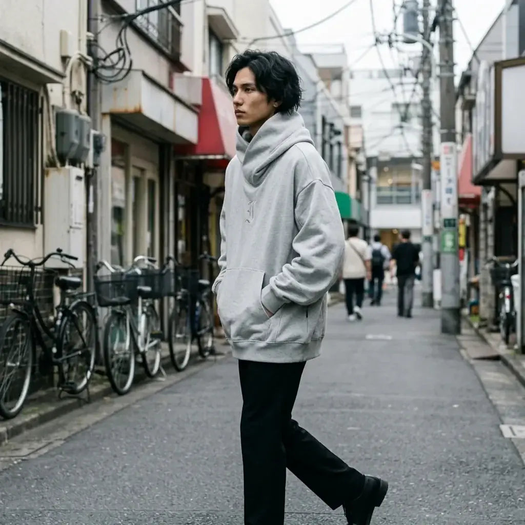 Sweat streetwear Harajuku en gris chiné, les épaules tombantes et les manches larges saisies en pleine marche.