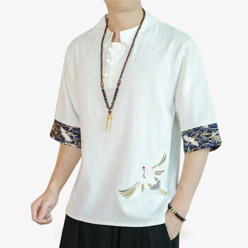 A man is dressed in a traditional-style white Japanese t-shirt. He is also wearing a jewellery chain around his neck.