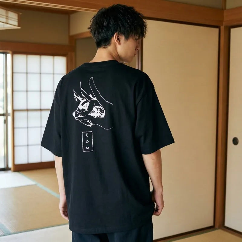 un homme porte un t-shirt Kon style manga de couleur noir dans une pièce japonaise