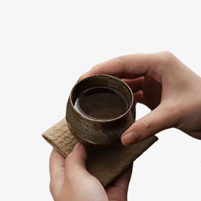 Deux mains tenant une tasse à matcha en céramique à l'esthétique intemporelle, idéale pour préparer et savourer le thé matcha traditionnel